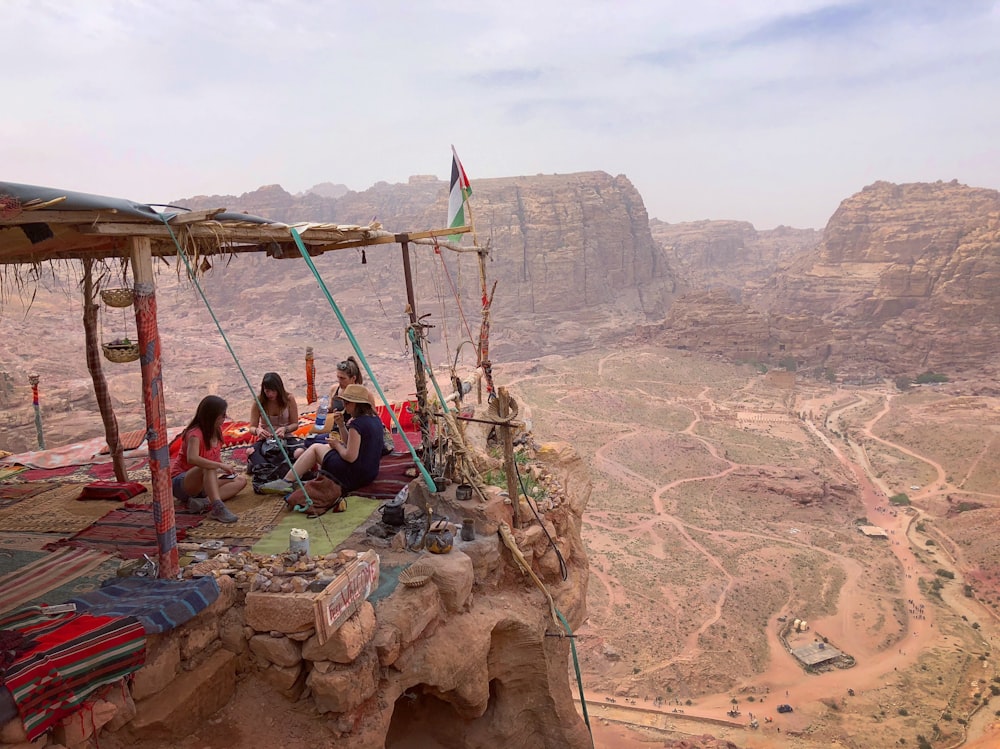 four person sitting on mountain hill during daytime