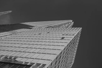 A sleek black and white photo of a modern construction site at dusk, highlighting steel frameworks against a dark sky.