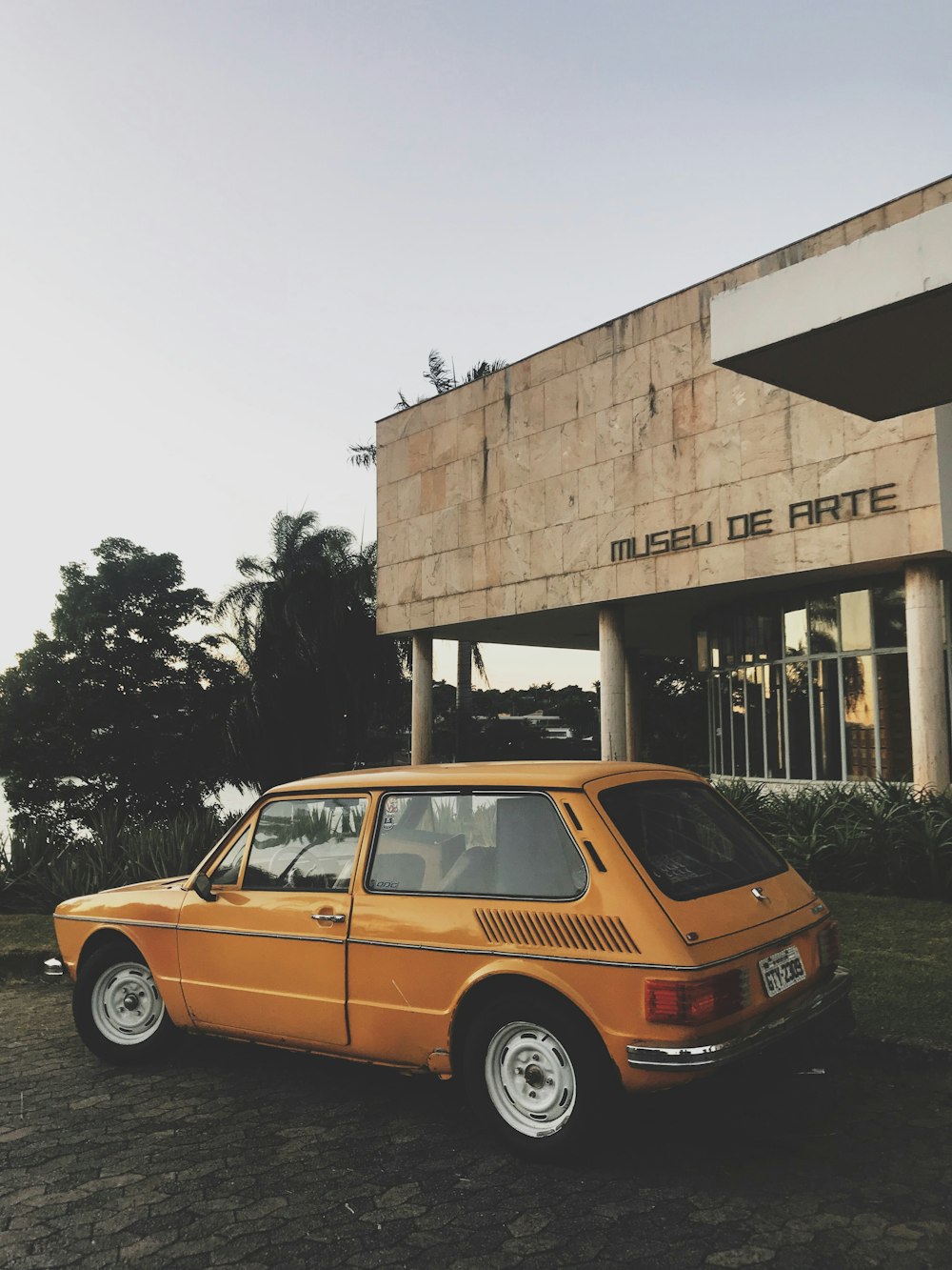 yellow station wagon parked on front of brown building