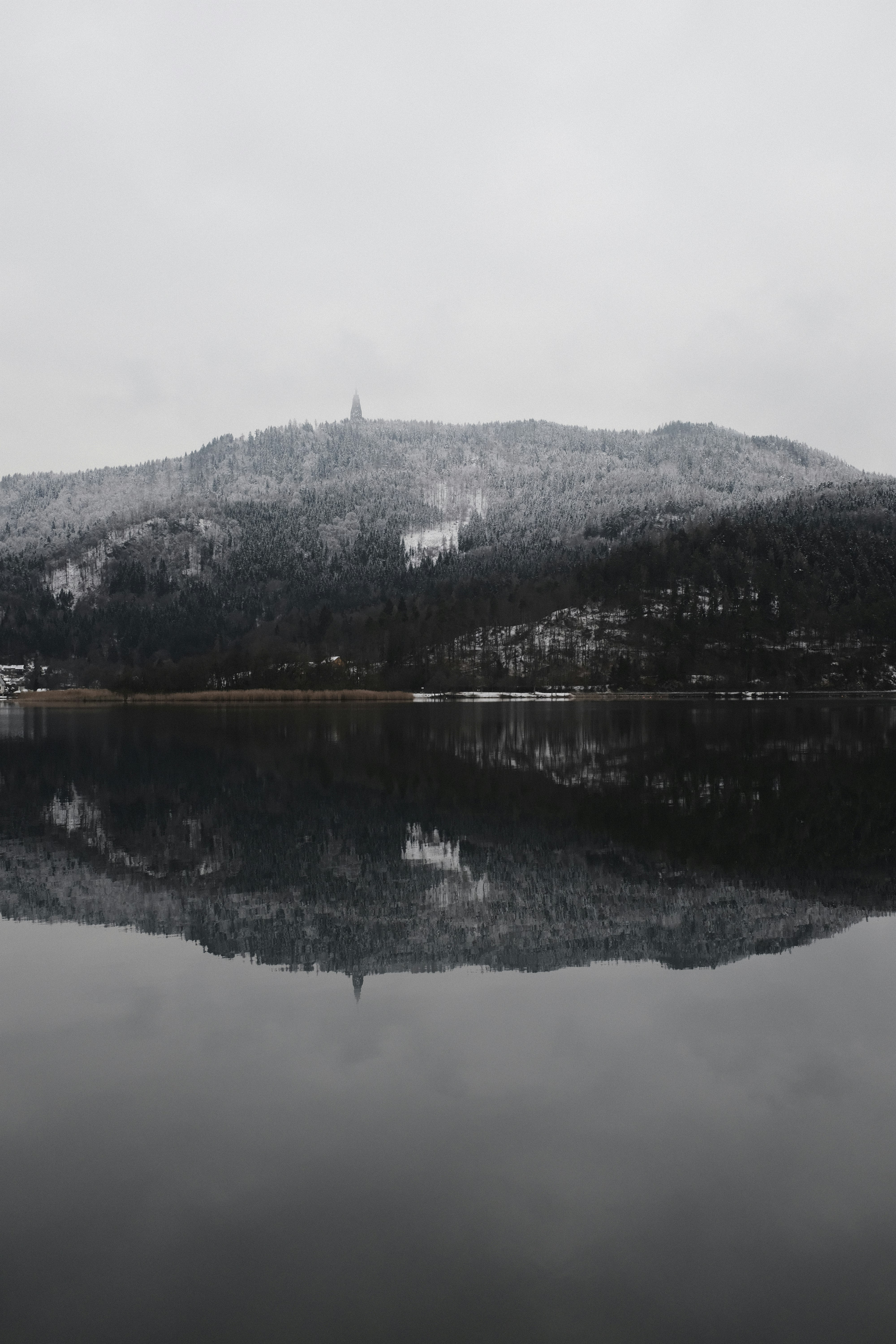 mountains reflected on calm body of water during daytime