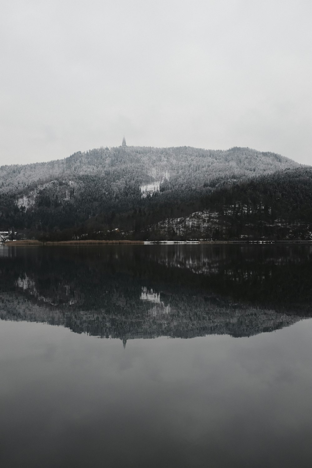 mountains reflected on calm body of water during daytime