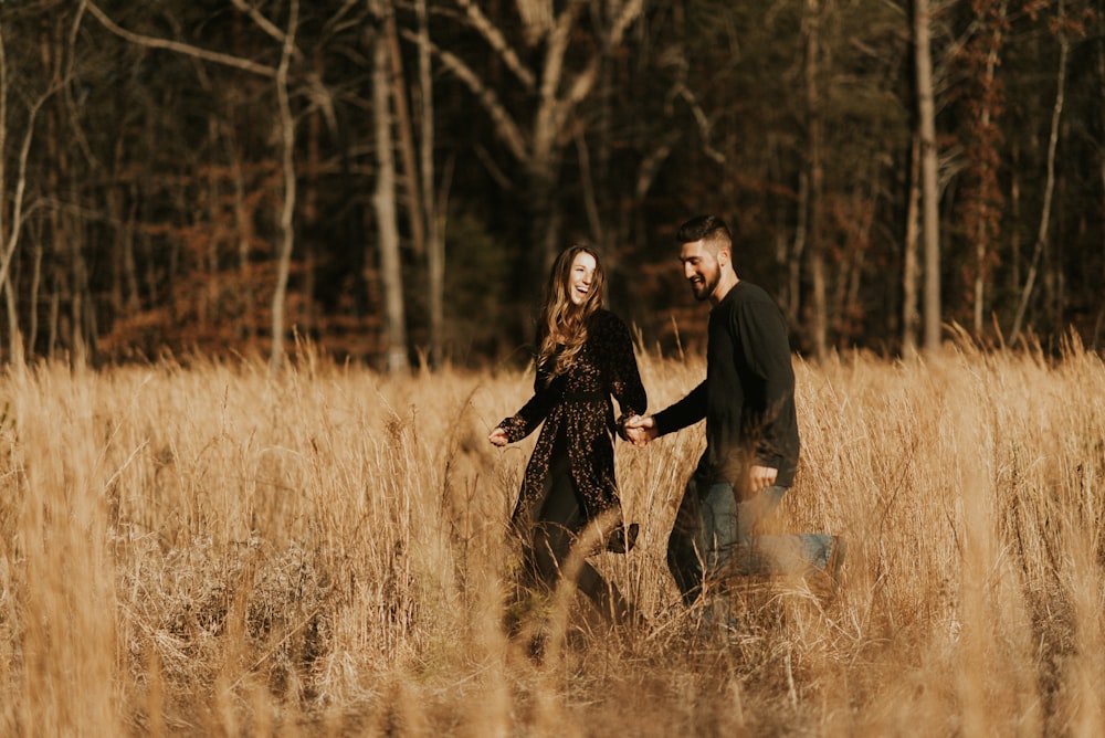 smiling man and woman walking on brown field