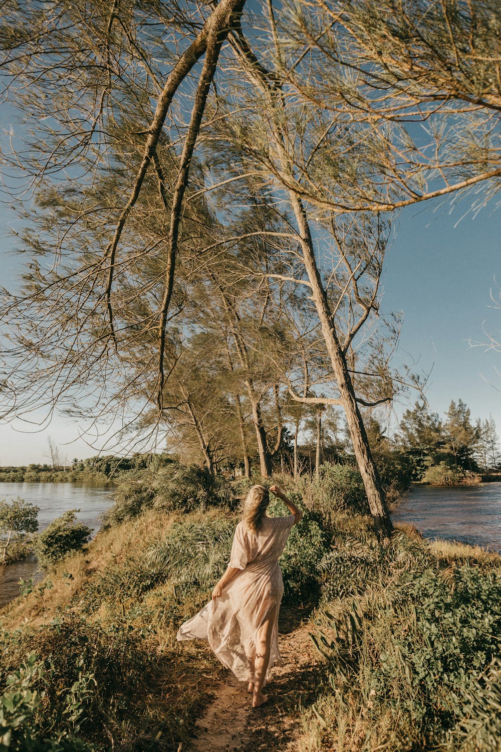 woman in white dress walking between grass