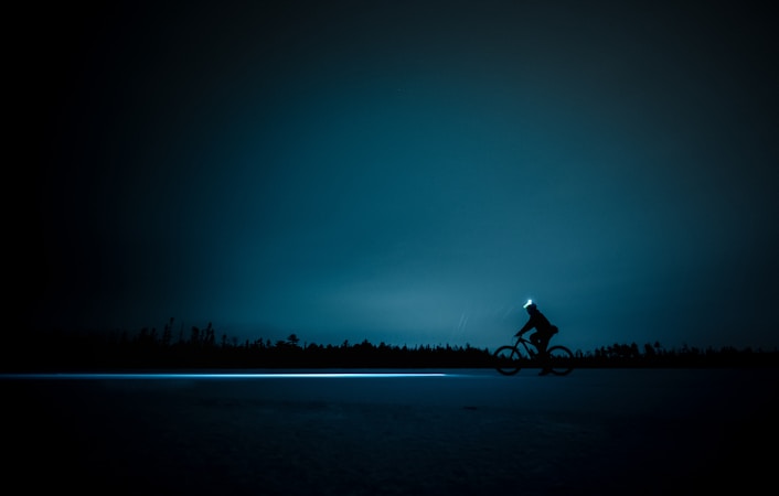 Night riding on a bikepacking route with bright bike lights illuminating a dark trail