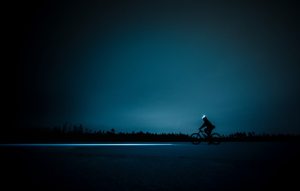 silhouette of person cycling during night