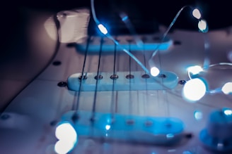 Close-up of a guitar with holiday lights wrapped around it.