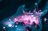 A vibrant guitar glowing under purple spotlights with sparkling stars around.