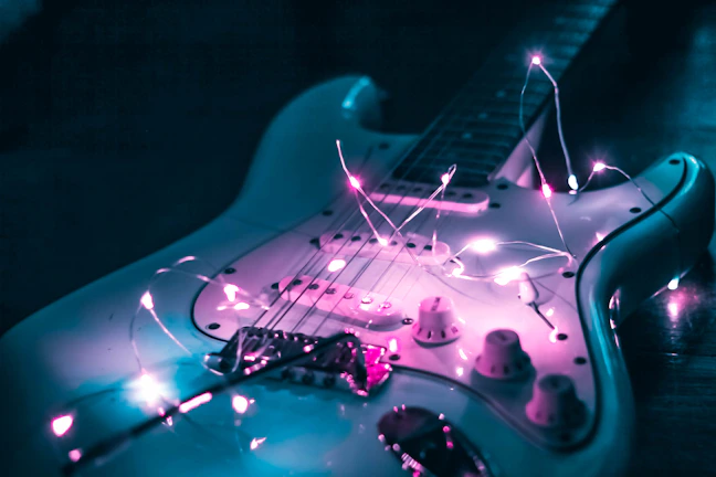 A vibrant guitar glowing under purple spotlights with sparkling stars around.