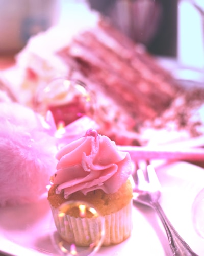 A close-up of a freshly baked pink frosted cake with delicate yellow sprinkles sitting on a pastel yellow plate.
