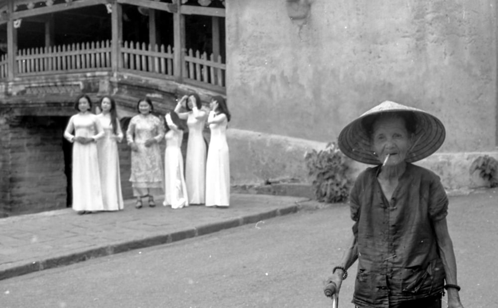 woman with hat near women standing by the wall