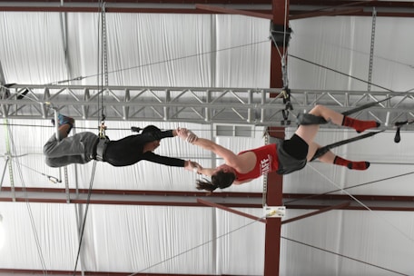 Adults engaged in aerial silks training in a spacious, welcoming gym.