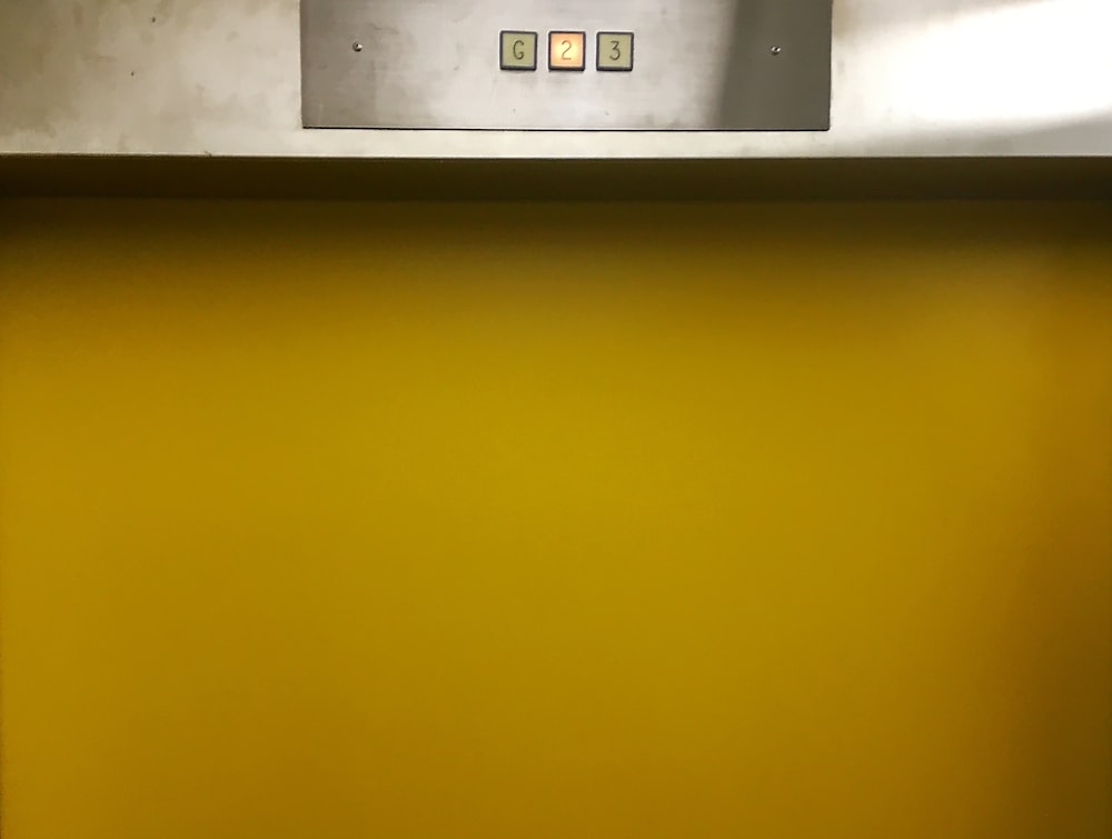 a bathroom with a yellow wall and a white toilet