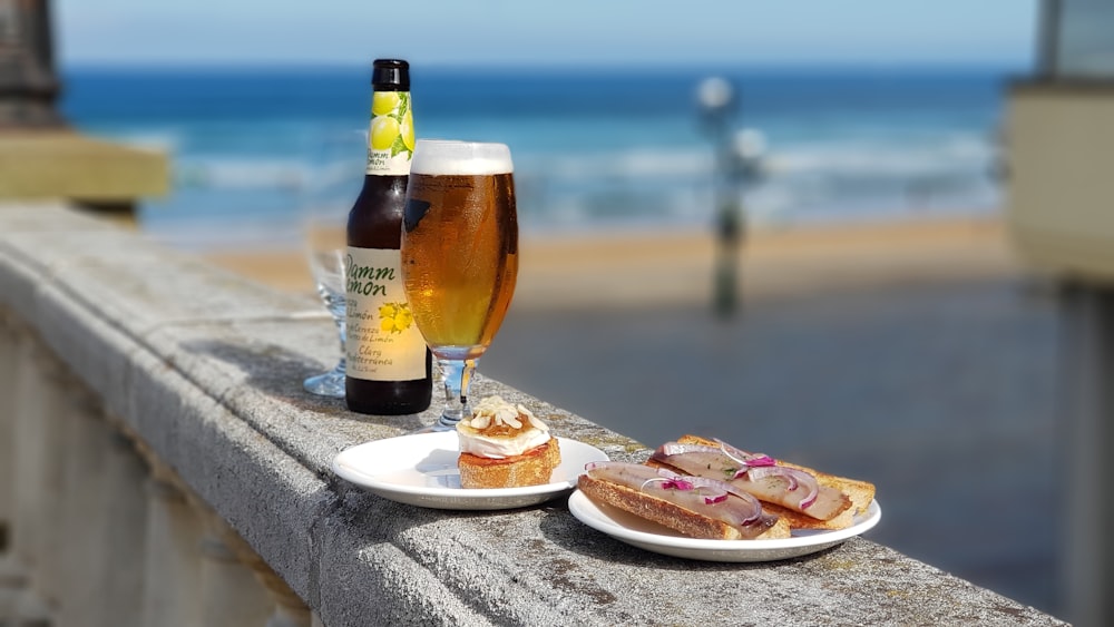 bread on plate beside glass of beer at daytime