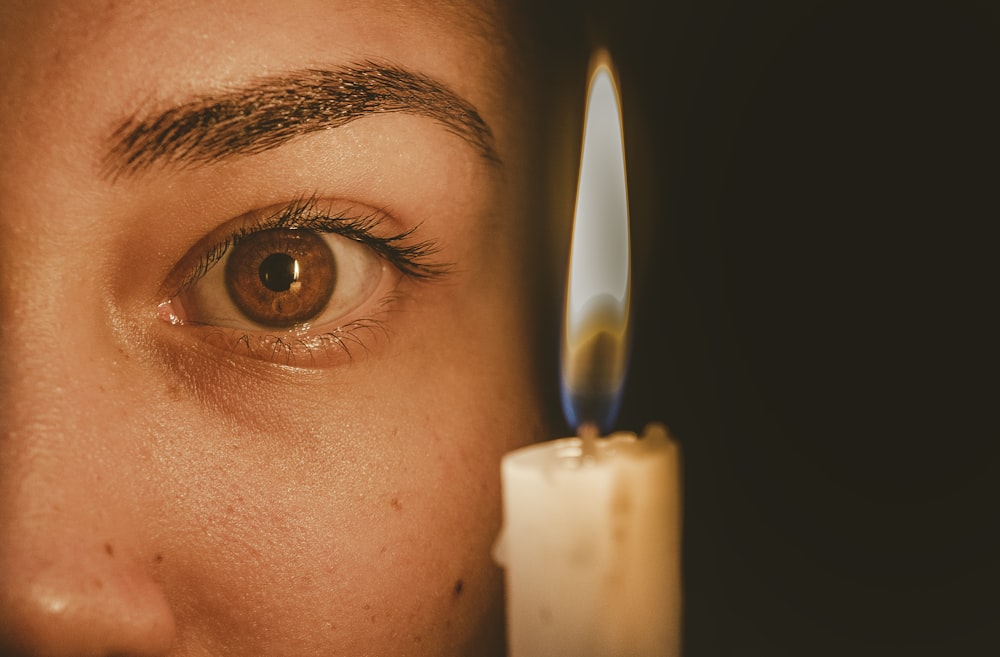 lighted candle beside human eye in close-up photography