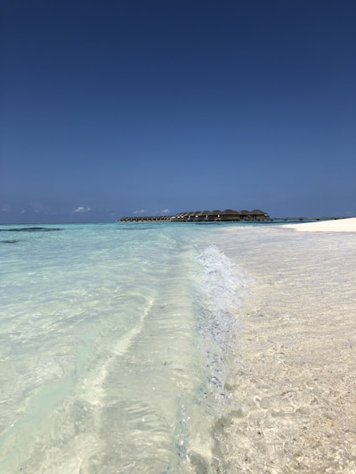 A serene beachfront villa at Koro Island Resort with turquoise waters gently lapping the shore under a clear blue sky.