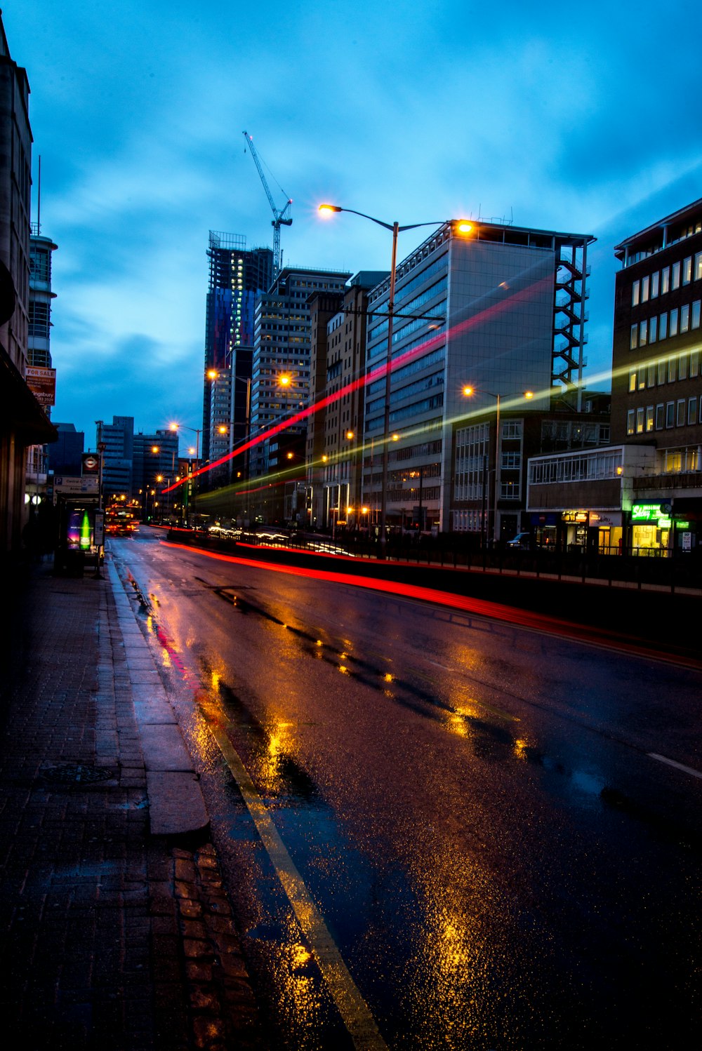 time lapse photography of road with city buildings under gray sky