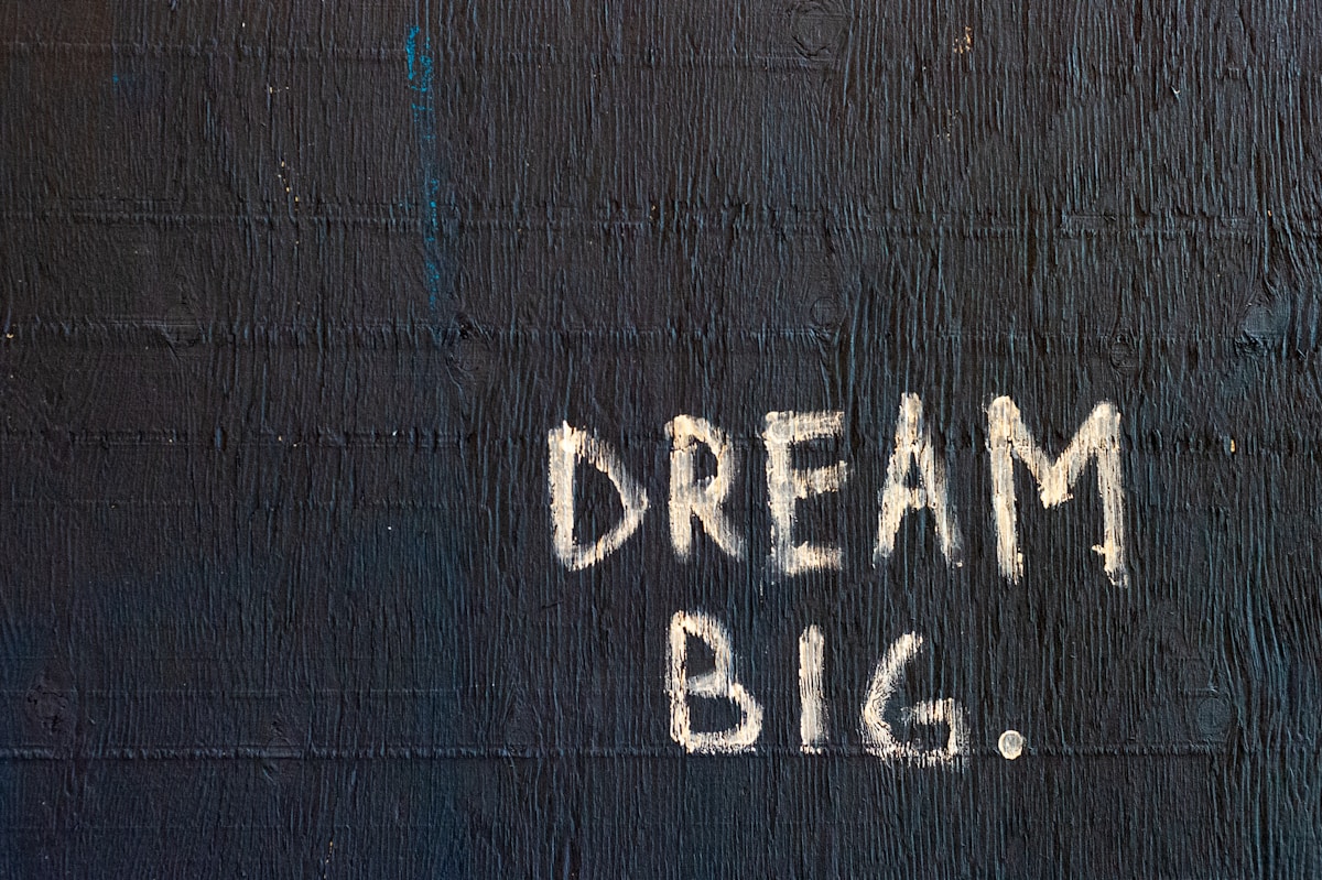 A black wall with the words DREAM BIG. in ivory paint.
