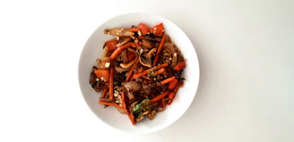 An inviting plate of traditional Chinese stir-fry with bright vegetables and tender meat, served in a classic blue and white bowl.