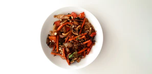 An inviting plate of traditional Chinese stir-fry with bright vegetables and tender meat, served in a classic blue and white bowl.