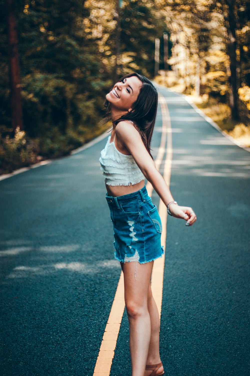 shallow focus photo of woman standing on the center of the road during daytime