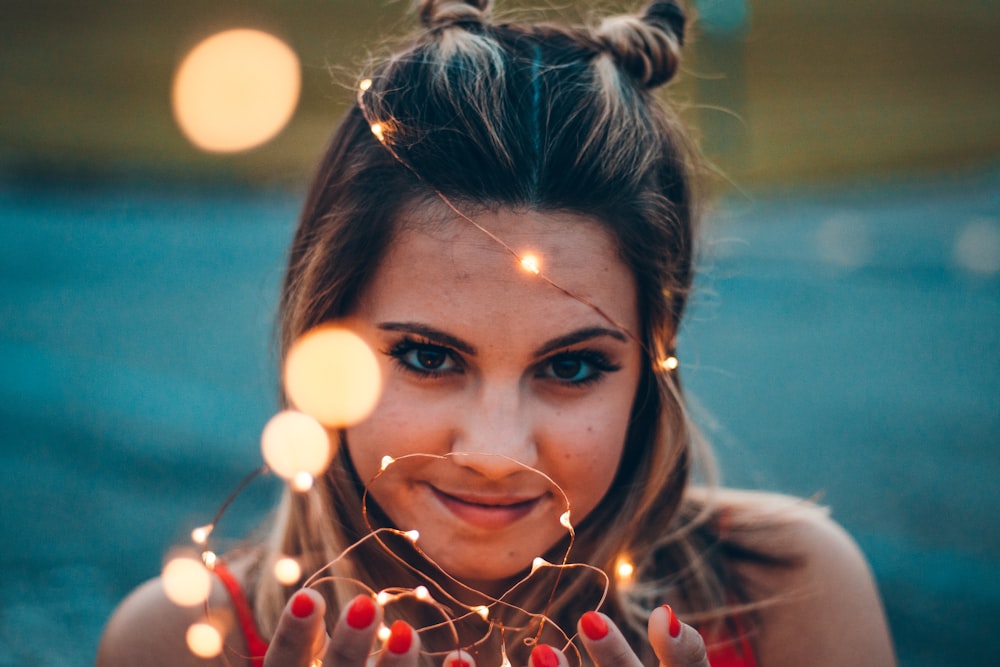 selective focus photography of woman holding string light