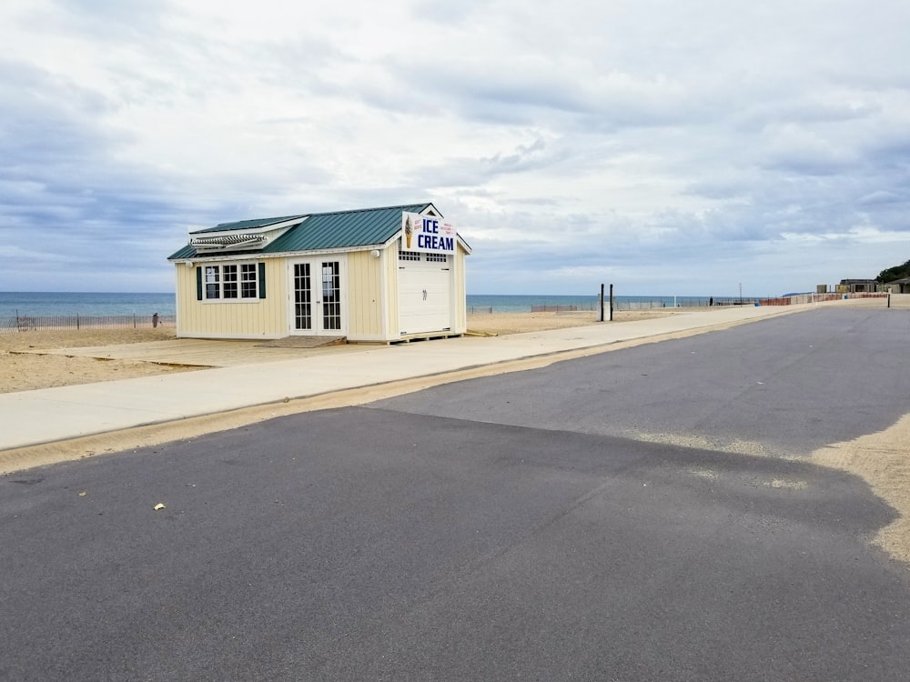 white ice cream parlor beside grey road under white cloudy sky