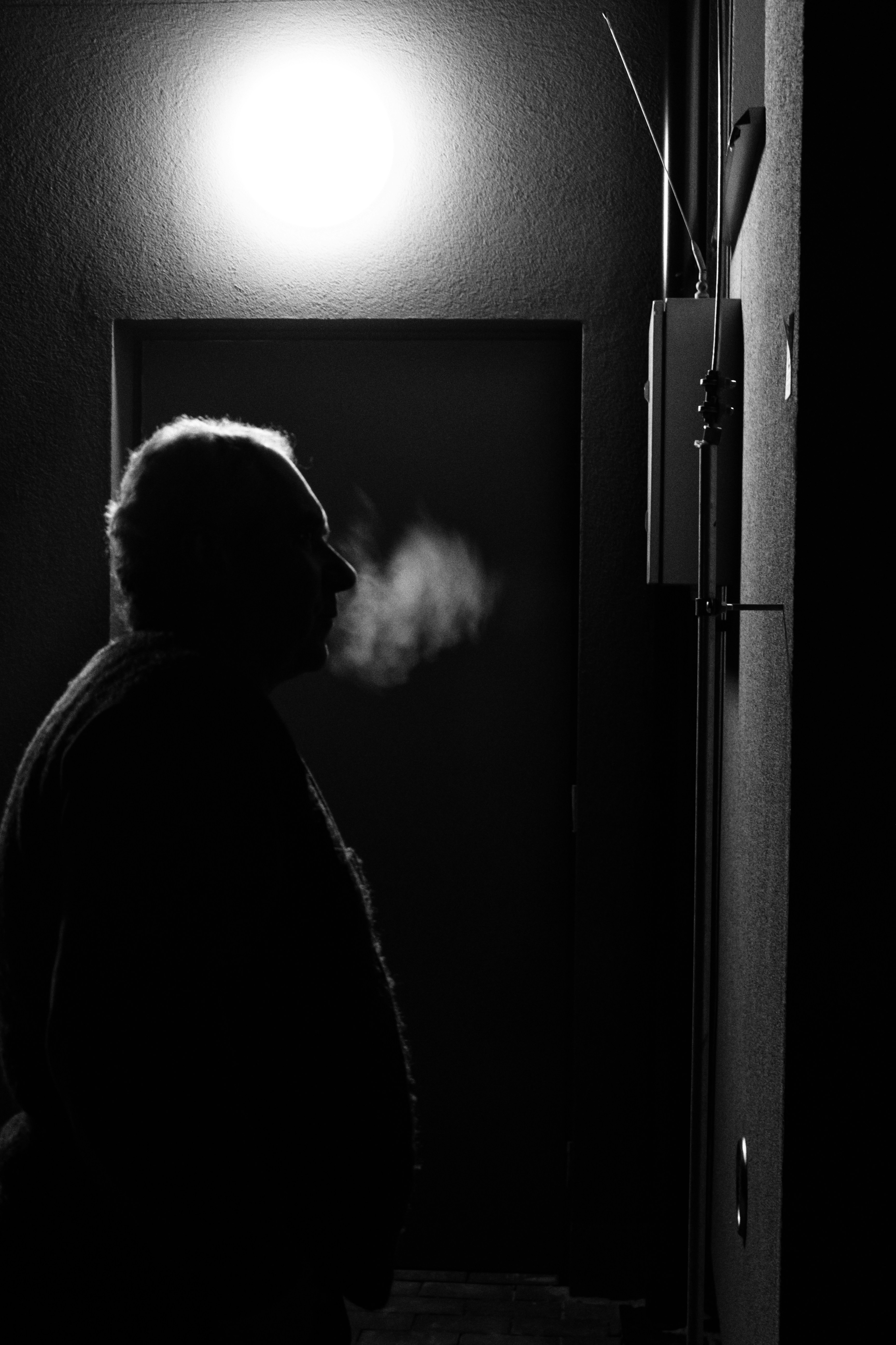 閉ざされたドアのそばに立つ男のグレースケール写真