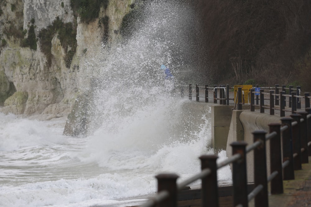 sea waves crashing trough gray road