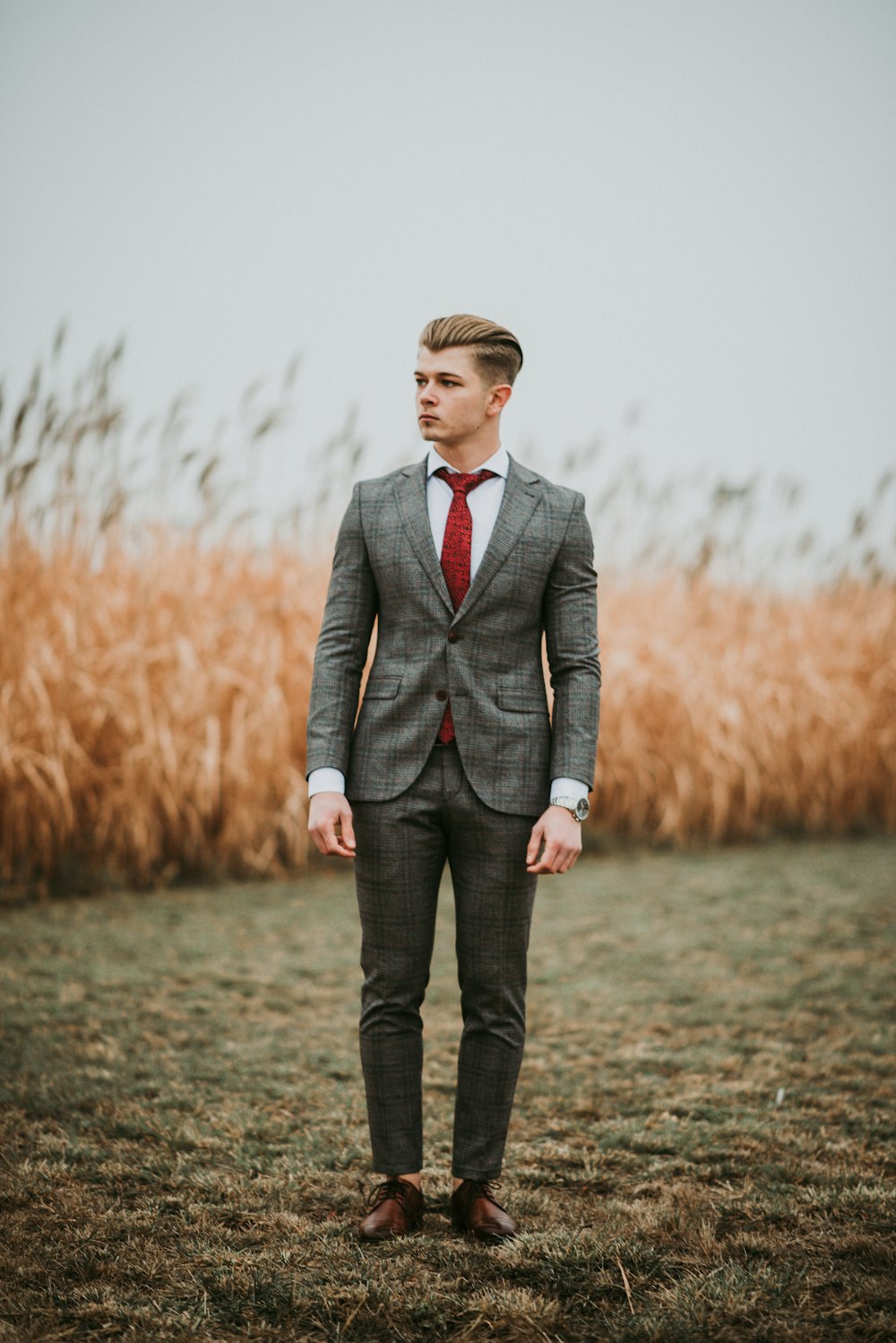선택적 초점 사진에 갈색 잔디 밭 근처에 서 있는 남자