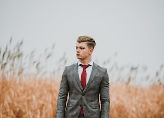 man standing near brown grass field on selective focus photography