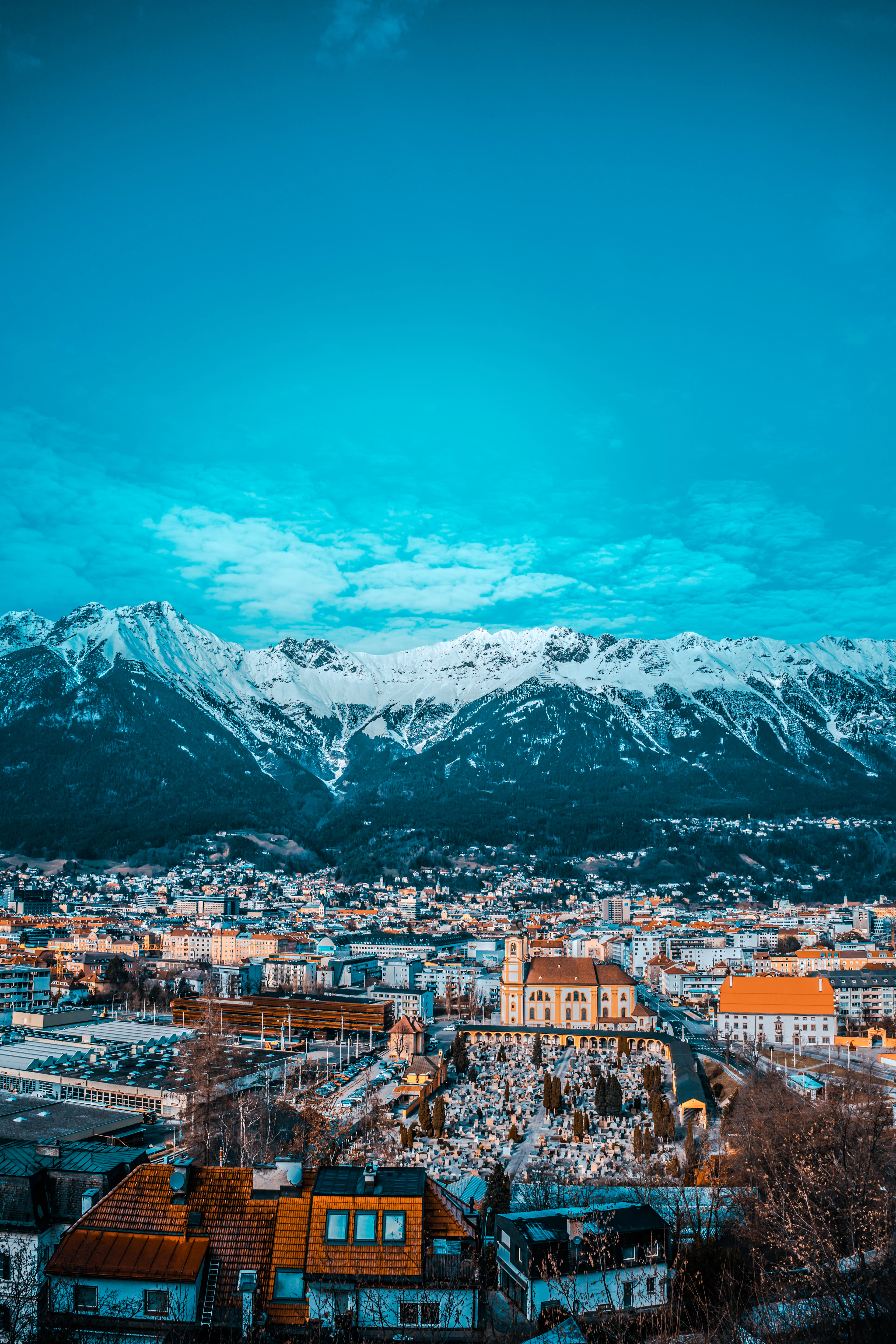 Rooftops of Innsbruck at dusk beneath the jagged, snow-capped peaks of the Nordkette mountains