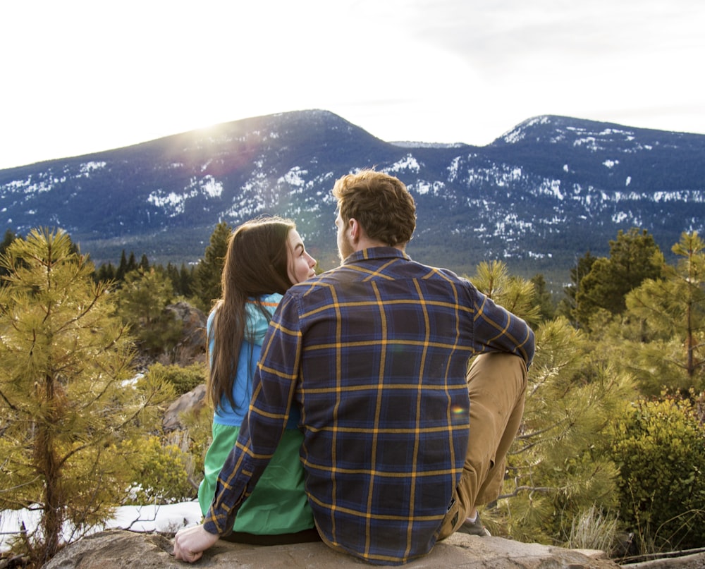 man and woman sitting on rack facing at mountain