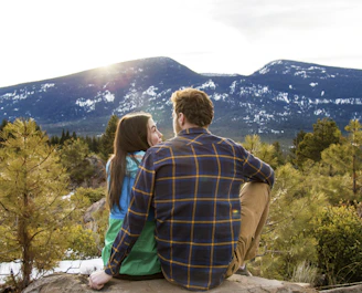 man and woman sitting on rack facing at mountain