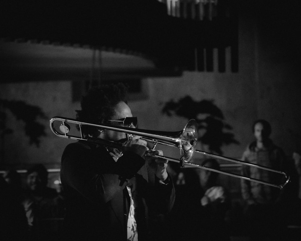 grayscale photography of man playing trumpet