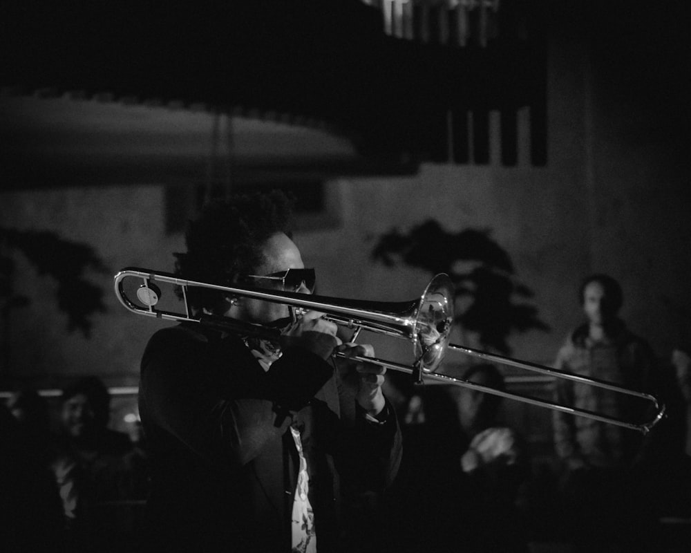 fotografia em tons de cinza do homem tocando trompete