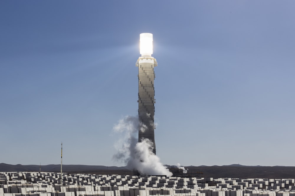 gray tower with smoke under gray clouds during daytime