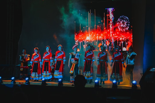 Performers on stage surrounded by dynamic red and gold lighting effects.