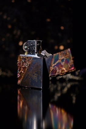 A modern torch lighter with triple flame, featuring a brushed metal finish against a black background