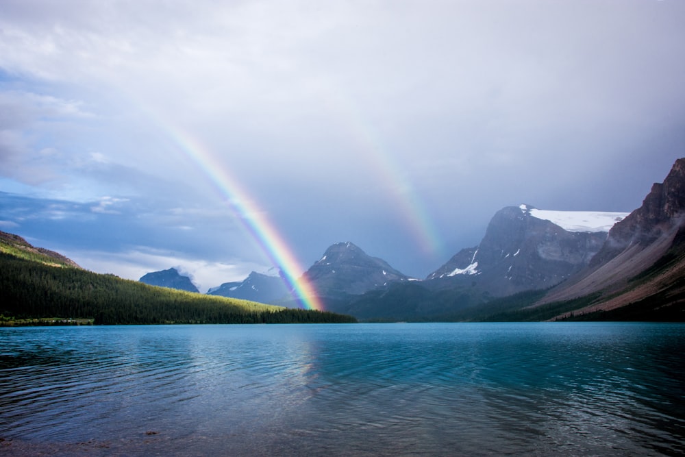 blue lake and rainbow under nimbus clouds