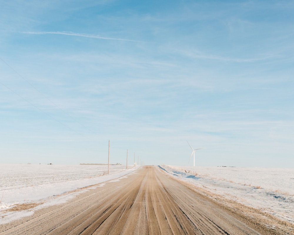 dirt-covered road between snow-covered ground during daytime