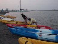 Children excitedly preparing their kayaks on a sandy shore before setting off.