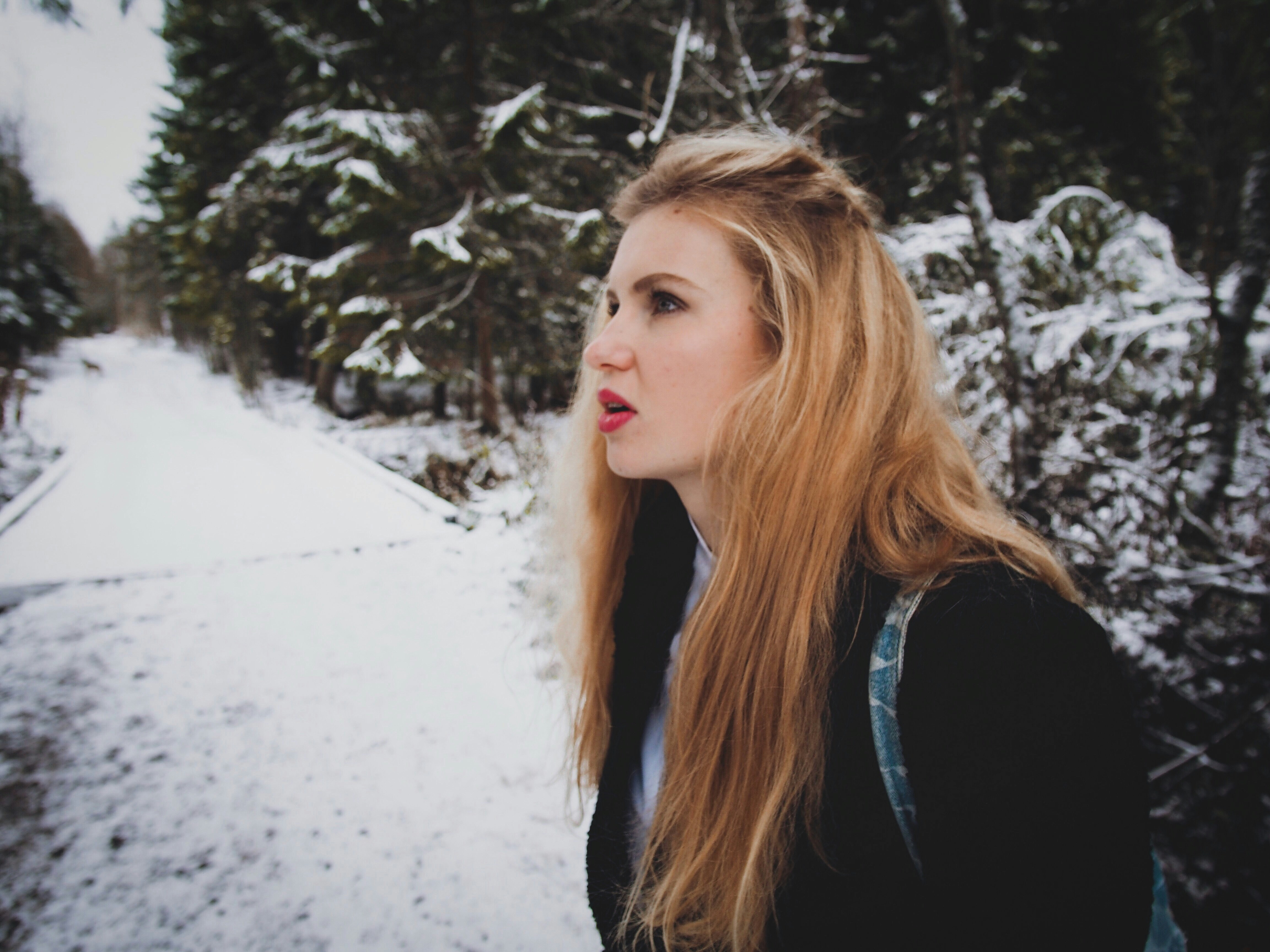 雪に覆われた地面に立つ黒いトップスを着た女性