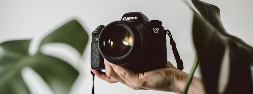 person holding Canon EOS DSLR camera