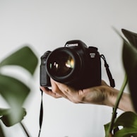 person holding Canon EOS DSLR camera