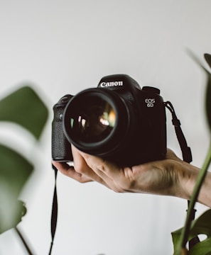 person holding Canon EOS DSLR camera