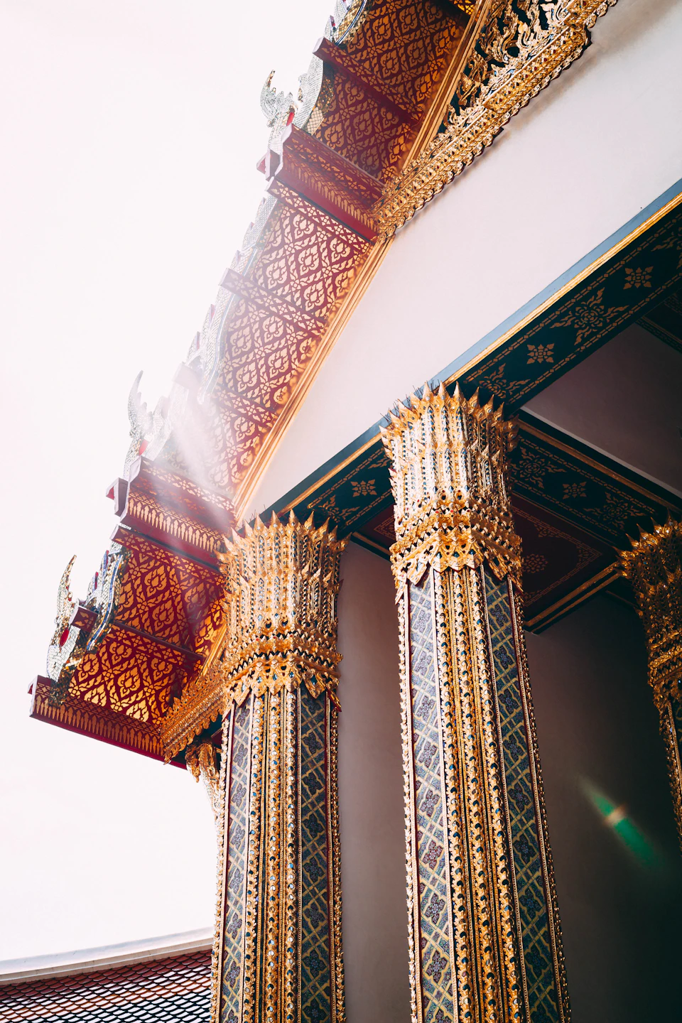 Temple with ornate columns and intricate designs in gold and red against white background