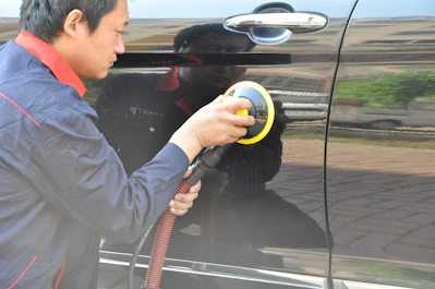 High-contrast slow-motion video still of expert applying ceramic coating on a luxury car.