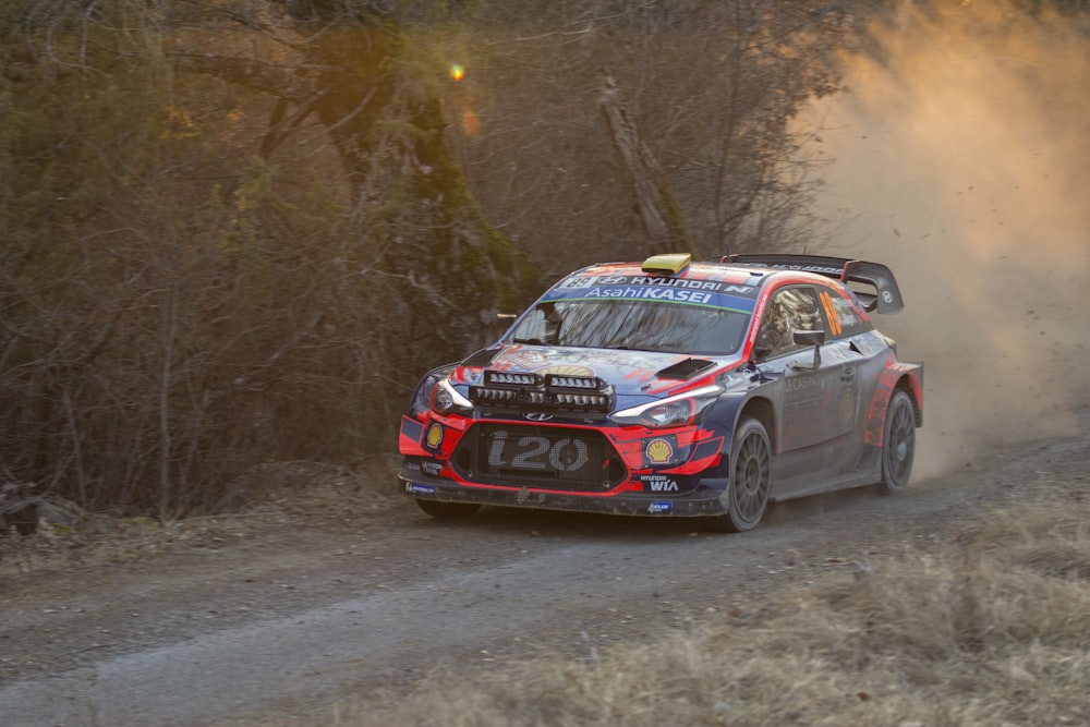 Coche de rally azul y rojo en camino de tierra durante el día