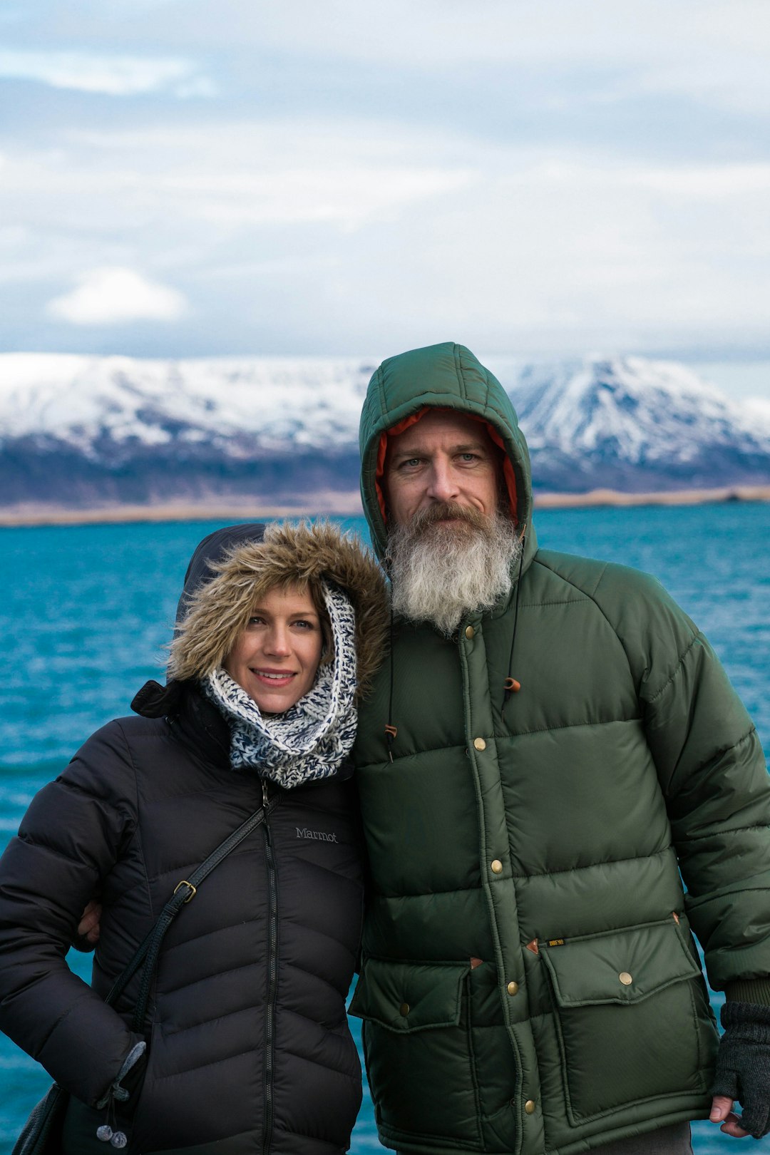 man and woman wearing bobble jackets near body of water