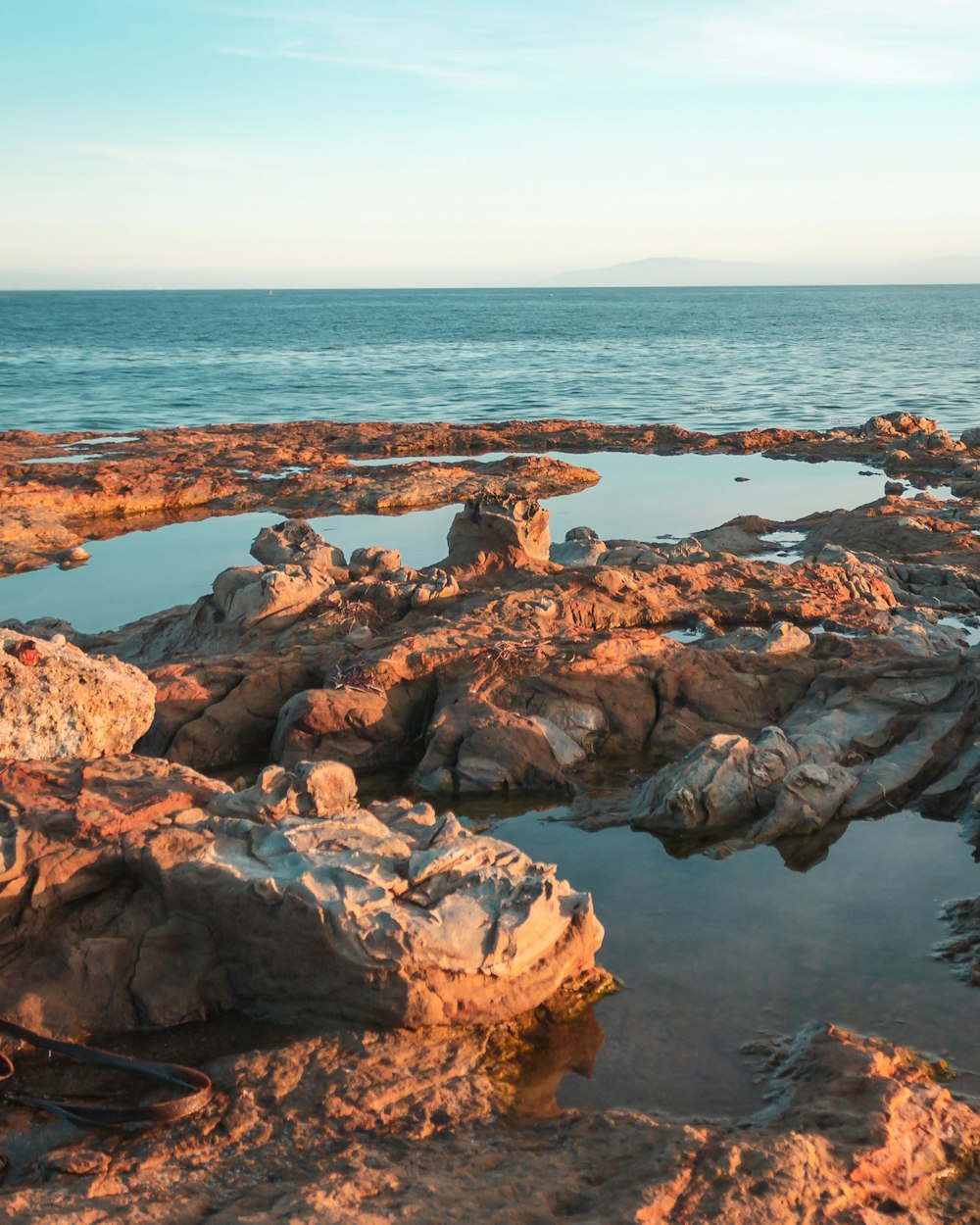 gray rock formation near calm body of water during daytime